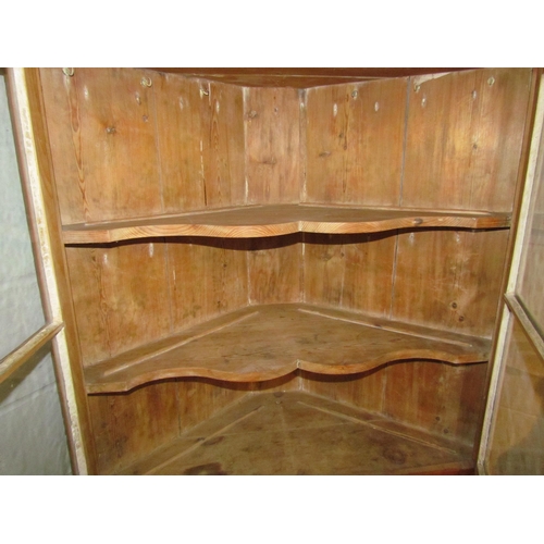 1010 - A Victorian pitch pine corner cupboard, the glazed doors opening to reveal shelved interior over two... 