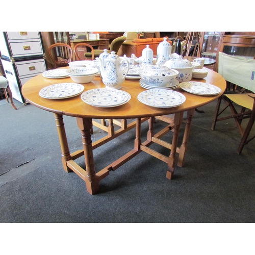 1027 - An 18th Century revival light oak circular top double gate-leg dining table the rising leaves over g... 