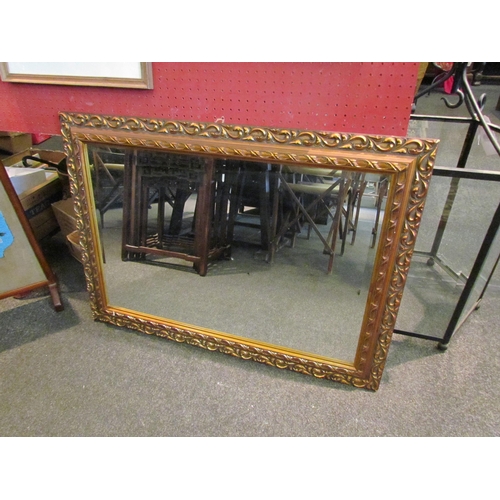 1082 - An ornate gilt framed bevel edge wall mirror, 64cm x 90cm total