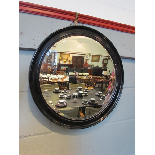 1104 - A circular wall mirror with ebonised frame, bevelled edge, 59cm diameter