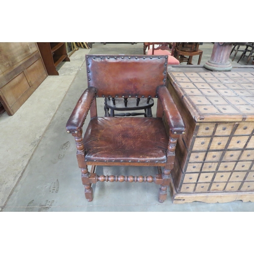 2185 - A 1920's Jacobean style oak elbow chair, worn leather seat