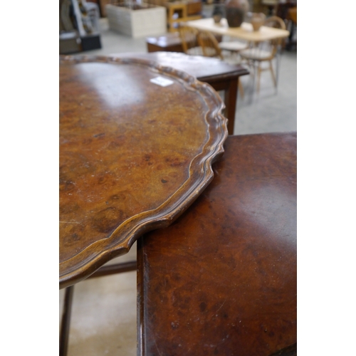 2244 - A 1930's walnut circular wavy edged coffee table with nest of four triangular tables