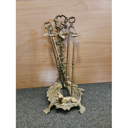 1227 - A brass fireside companion with gun and dog design along with associated attachments, 56cm tall