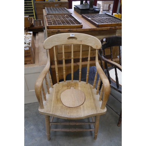 2005 - A 1920's oak spindle back Captain's chair with cut-out hole to seat