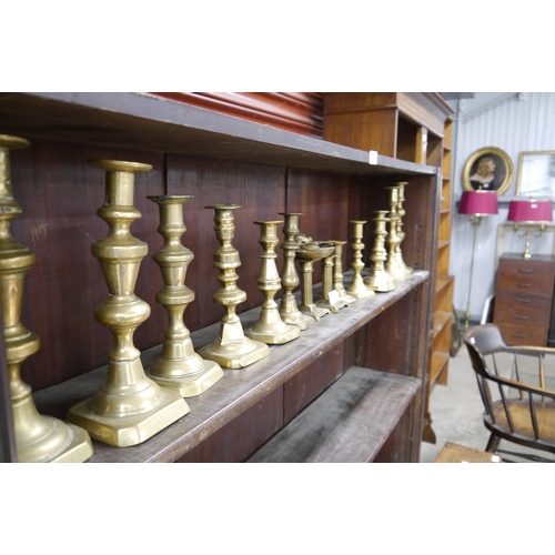 2103 - Fourteen brass candlesticks to include ejector, and a brass mask ashtray