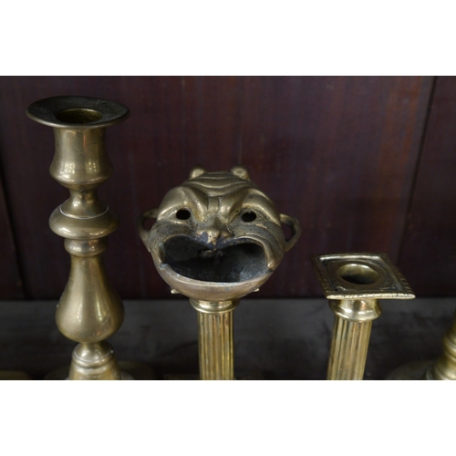 2103 - Fourteen brass candlesticks to include ejector, and a brass mask ashtray