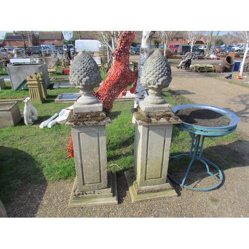 5464 - A pair of weathered composition plinths with pineapple finials, 60