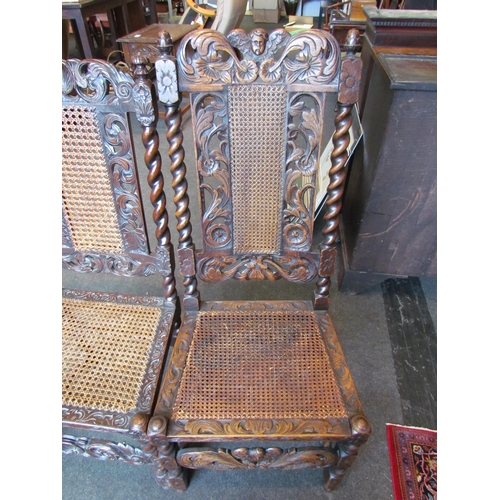 1025 - Two similar heavily carved oak barley-twist chairs with cane seats and backrests