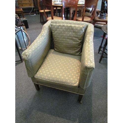 1109 - An early 20th Century armchair, square arms, green patterned upholstery, on square legs to castors