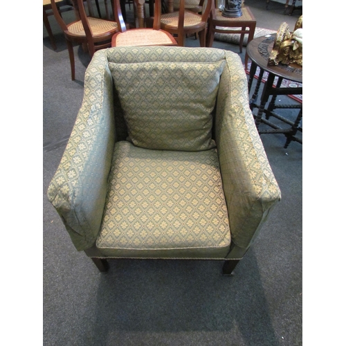 1109 - An early 20th Century armchair, square arms, green patterned upholstery, on square legs to castors