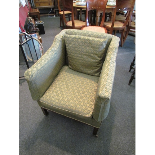 1109 - An early 20th Century armchair, square arms, green patterned upholstery, on square legs to castors