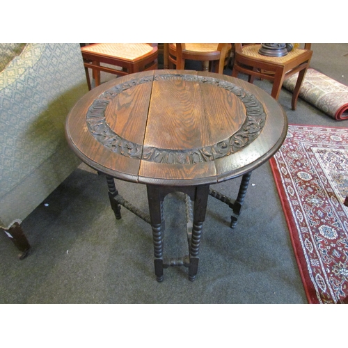 1111 - A carved oak drop-leaf occasional table on bobbin turned supports