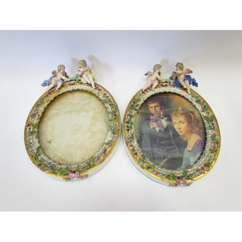 1178 - A pair of floral encrusted porcelain picture frames surmounted by cherubs, crossed sword marks to to... 