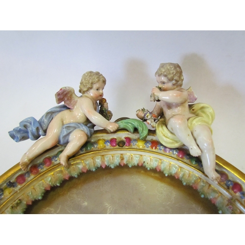 1178 - A pair of floral encrusted porcelain picture frames surmounted by cherubs, crossed sword marks to to... 