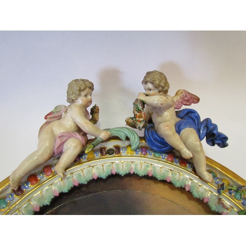 1178 - A pair of floral encrusted porcelain picture frames surmounted by cherubs, crossed sword marks to to... 