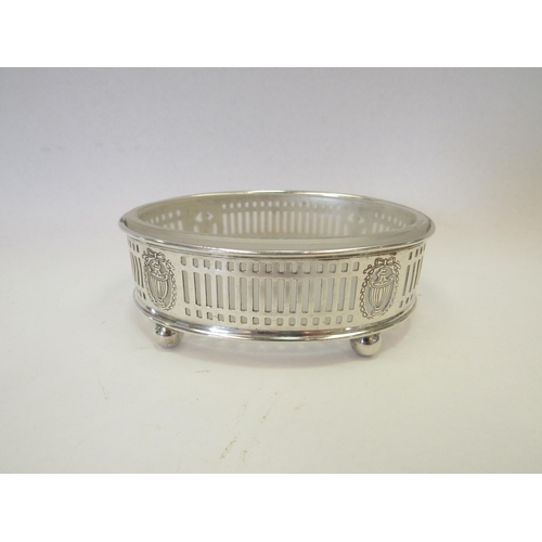 1315 - A pierced silver glass lined butter dish of oval form with engraved floral and urn design on four ba... 