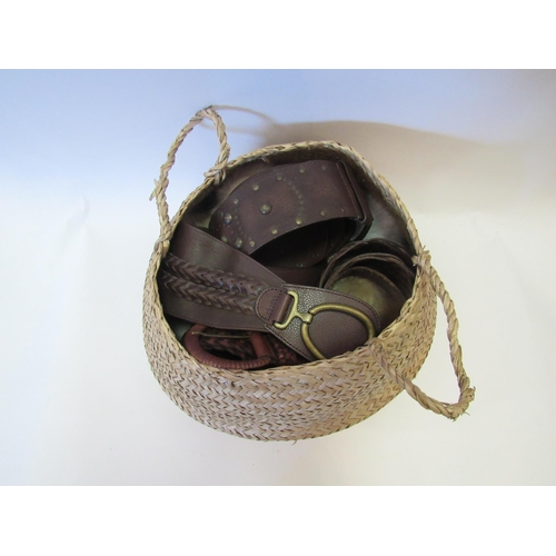 1276 - A woven seagrass basket containing a quantity of leather belts, etc