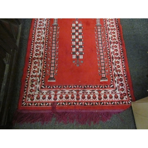 1102 - A Turkish red ground prayer rug with purple tasselled ends, some tassels missing, 118cm x 69cm