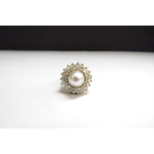 7009 - An 18ct gold pearl and diamond ring, the centre pearl 9mm framed by two rows of brilliant cut diamon... 
