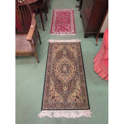 4076 - A small black and gold rug with foliate design and tasselled ends, 135cm x 69cm, together with a red... 