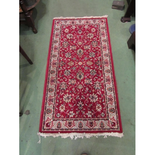 4076 - A small black and gold rug with foliate design and tasselled ends, 135cm x 69cm, together with a red... 