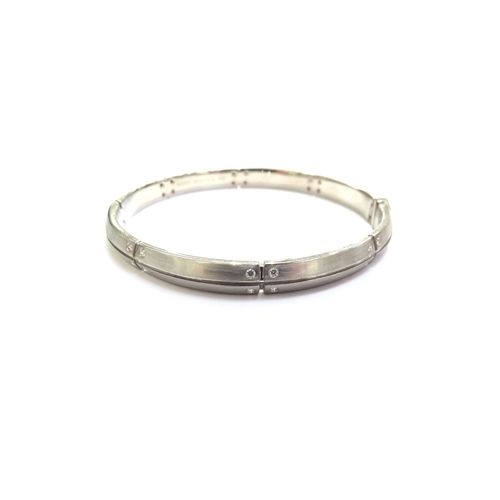 7063 - A Tiffany and Co 2000 white gold diamond set hinged bangle, marked 750, satin finish, 5.5cm x 5.3cm,... 