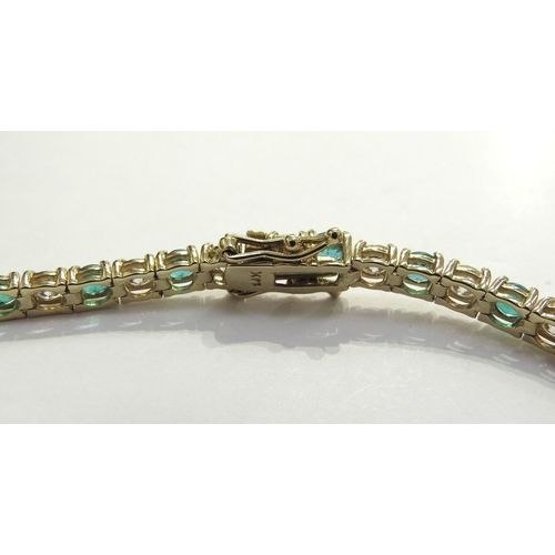 7039 - An emerald and diamond line bracelet all in four claw mounts, having 22 alternate set emeralds (3.74... 