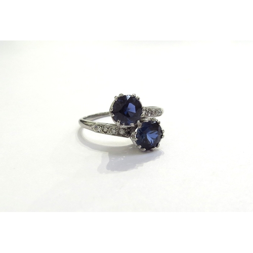 7391 - A sapphire and diamond crossover ring the two round cut sapphires, 5mm in diameter with diamond set ... 