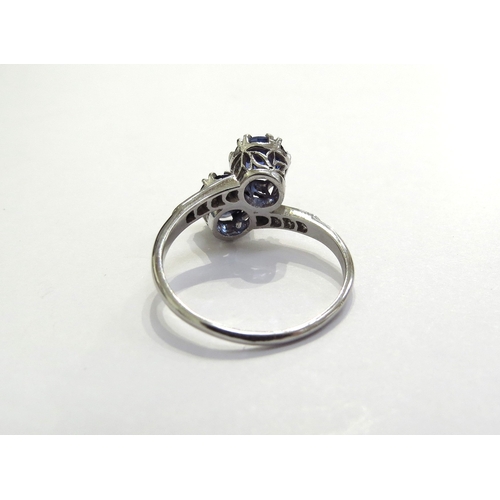 7391 - A sapphire and diamond crossover ring the two round cut sapphires, 5mm in diameter with diamond set ... 