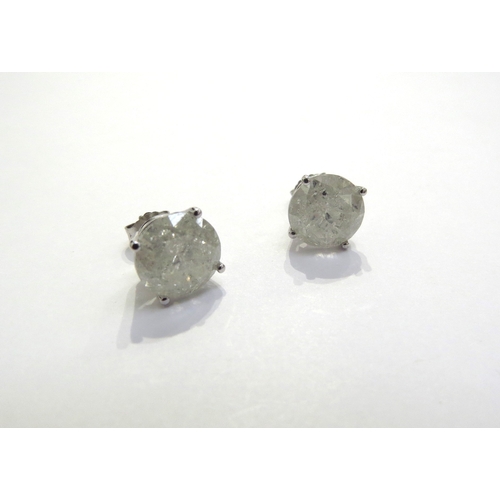 7385 - A pair of diamond stud earrings in four claw mount, 3ct approx each stud, cloudy, with all over fiss... 