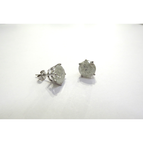 7385 - A pair of diamond stud earrings in four claw mount, 3ct approx each stud, cloudy, with all over fiss... 