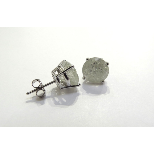 7385 - A pair of diamond stud earrings in four claw mount, 3ct approx each stud, cloudy, with all over fiss... 