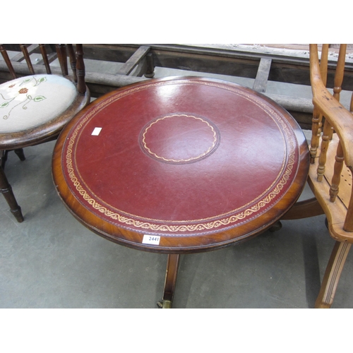 2441 - A Regency style coffee table of circular form, tooled red leather top, outswept supports with brass ... 