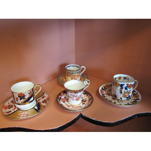 1140 - Nine coffee cans (mainly Imari palette) to include a silver cased Aynsley example, Royal Crown Derby... 