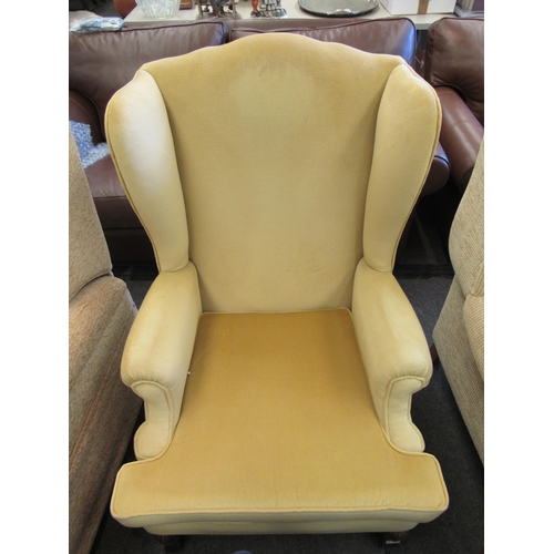 1101 - A gold velour wingback armchair with loose cushion seat, oak bulbous legs to square feet