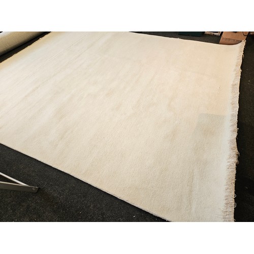 1402 - An Indian hand-knotted cream wool rug with tasselled ends, 320cm x 274cm