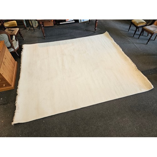 1403 - An Indian hand-knotted cream wool rug with tasselled ends, 320cm x 274cm