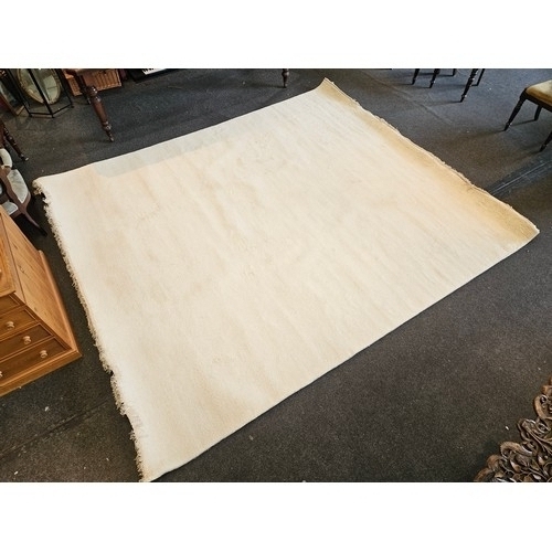 1403 - An Indian hand-knotted cream wool rug with tasselled ends, 320cm x 274cm