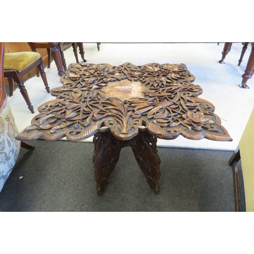 1102 - A heavily carved Anglo-Indian table decorated with central star, scrolling foliage, folding base, 58... 