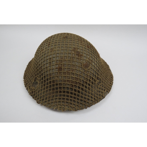 8138 - A WWII British Brodie helmet with camouflage net cover, the liner dated 1940, with chinstrap