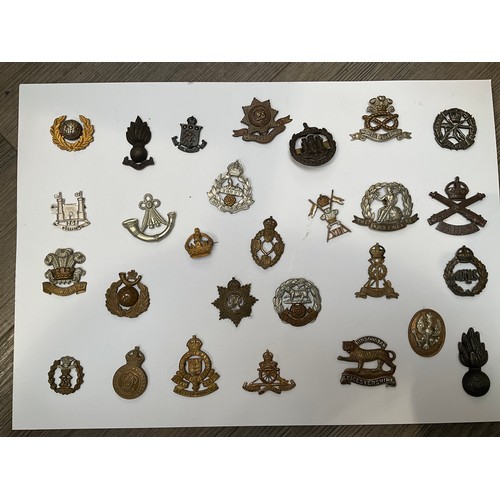 8552 - A display of British military badges including East Lancashire and Suffolk Regiment