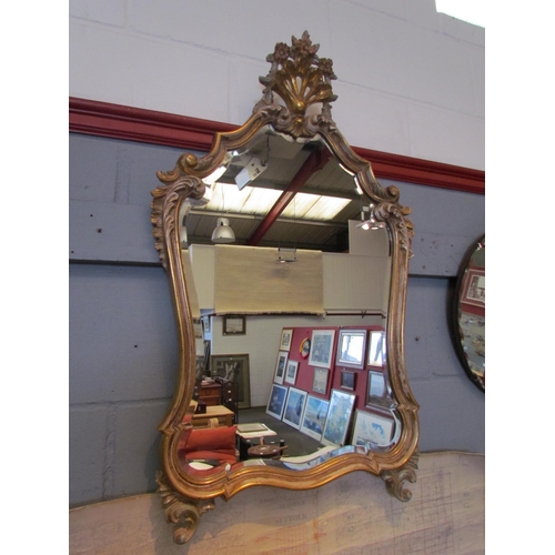 1062 - A reproduction Italian classical gilt wall mirror with floral crest and scrolled foliate mounts, 92c... 