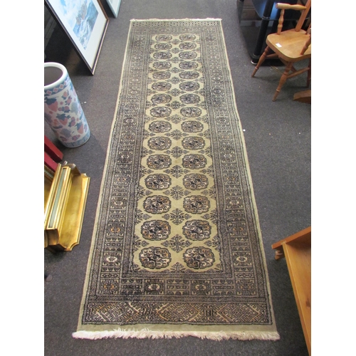 1084 - A green ground geometric design runner rug with two rows of lozenges and multiple borders with tasse... 