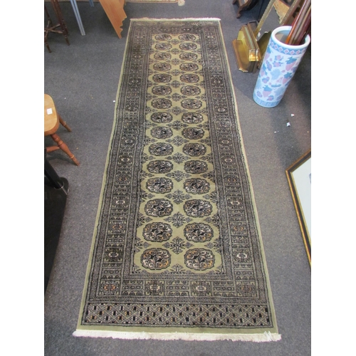 1084 - A green ground geometric design runner rug with two rows of lozenges and multiple borders with tasse... 