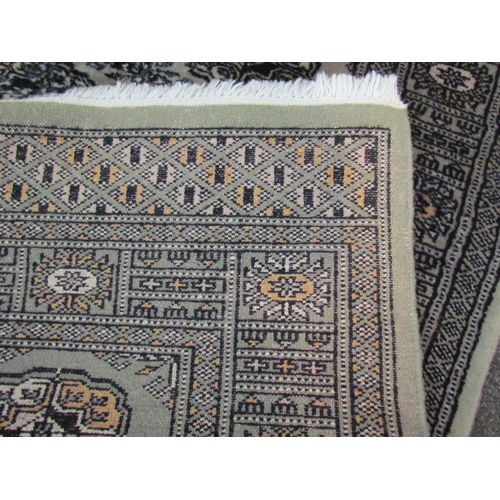 1084 - A green ground geometric design runner rug with two rows of lozenges and multiple borders with tasse... 