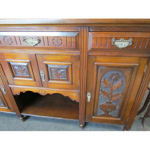 1107 - An Edwardian mahogany carved sideboard, three drawers above three cupboards with carved floral doors... 