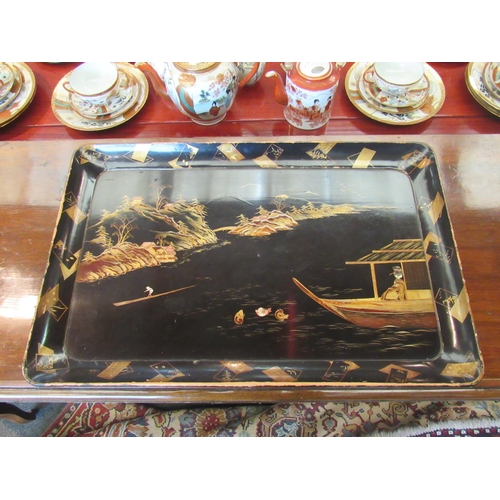 1106 - A Japanese black lacquered tray with scene of figures on boats by mountains, 62cm long