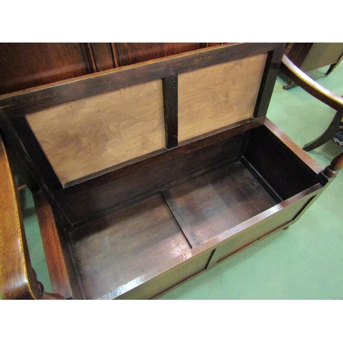 4162 - An Edwardian panelled oak box seat settle with carved decoration over a hinged seat and baluster tur... 