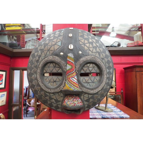 4094 - A 20th Century African mask with beaded and shell detailing, 38cm diameter