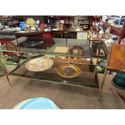 4011 - A 1970's two-tier smoked glass and brass frame occasional table with mirror borders, 46cm tall x 101... 